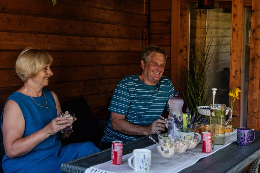 Iäkäs aviopari nauraa yhdessä puutarhapöydän ääressä